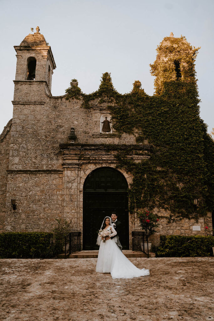 a bride and groom pose in front of their miami wedding venue