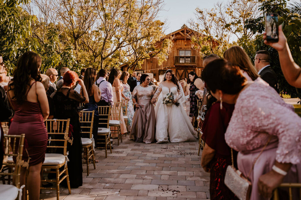a bride walks down the aisle at her wedding day at Hacienda Los Robles surrounded by family and friends