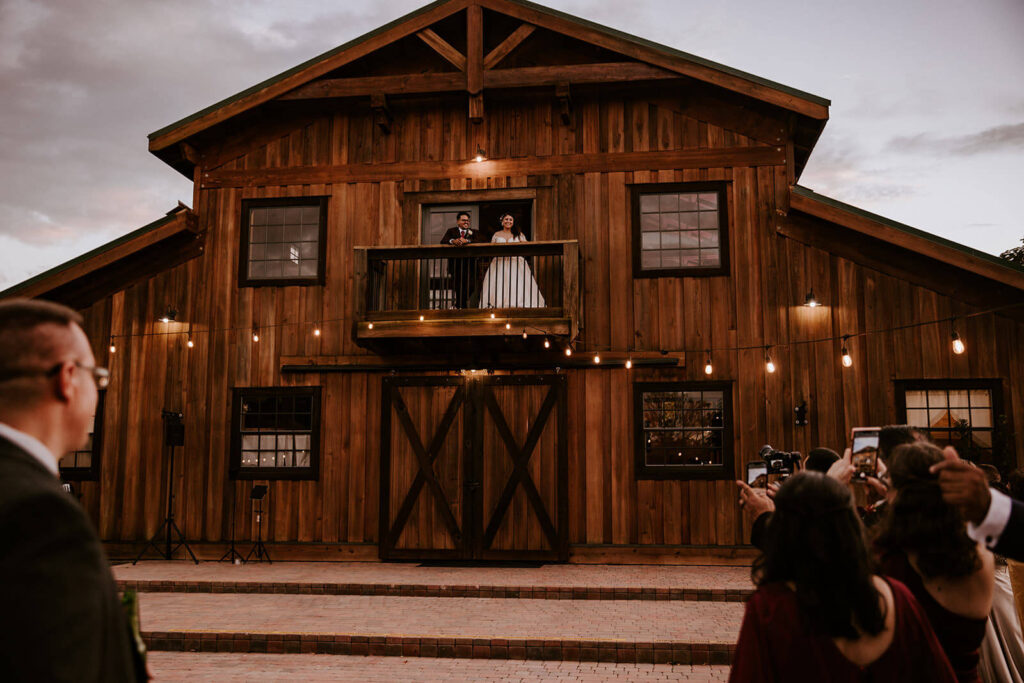 a couple standing on the balcony of their miami wedding venue overlooking their guests
