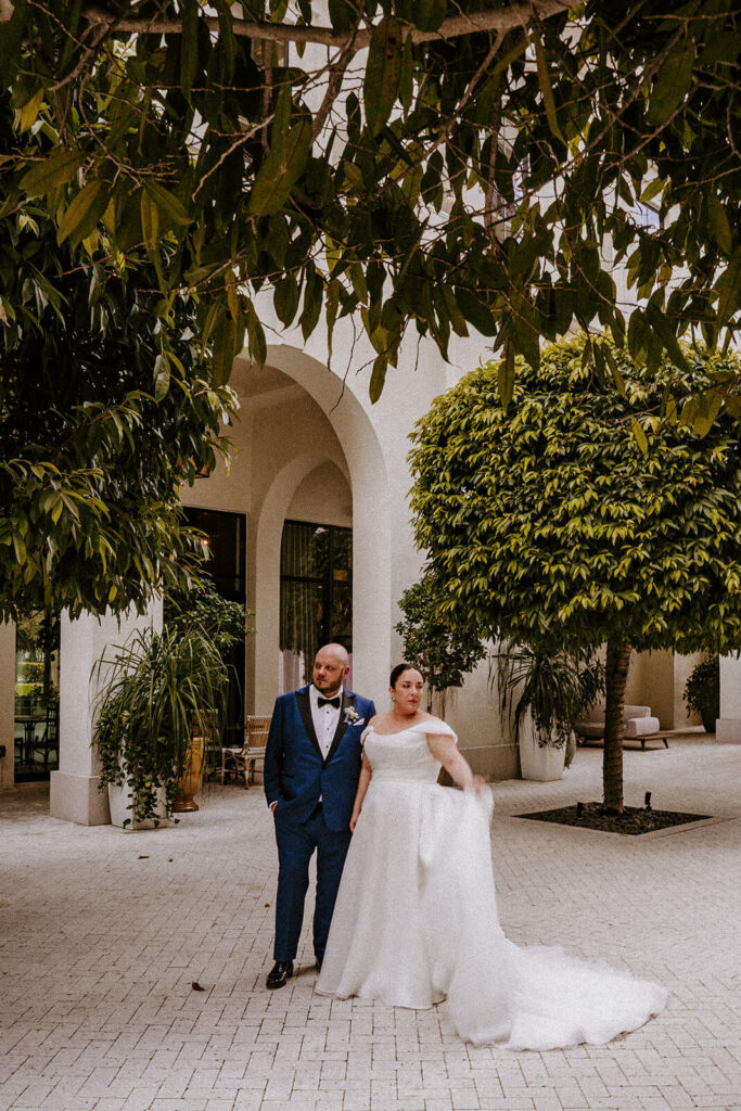 a couple poses with while looking opposite ways and holding her dress on their wedding day at The Thesis Hotel in Miami