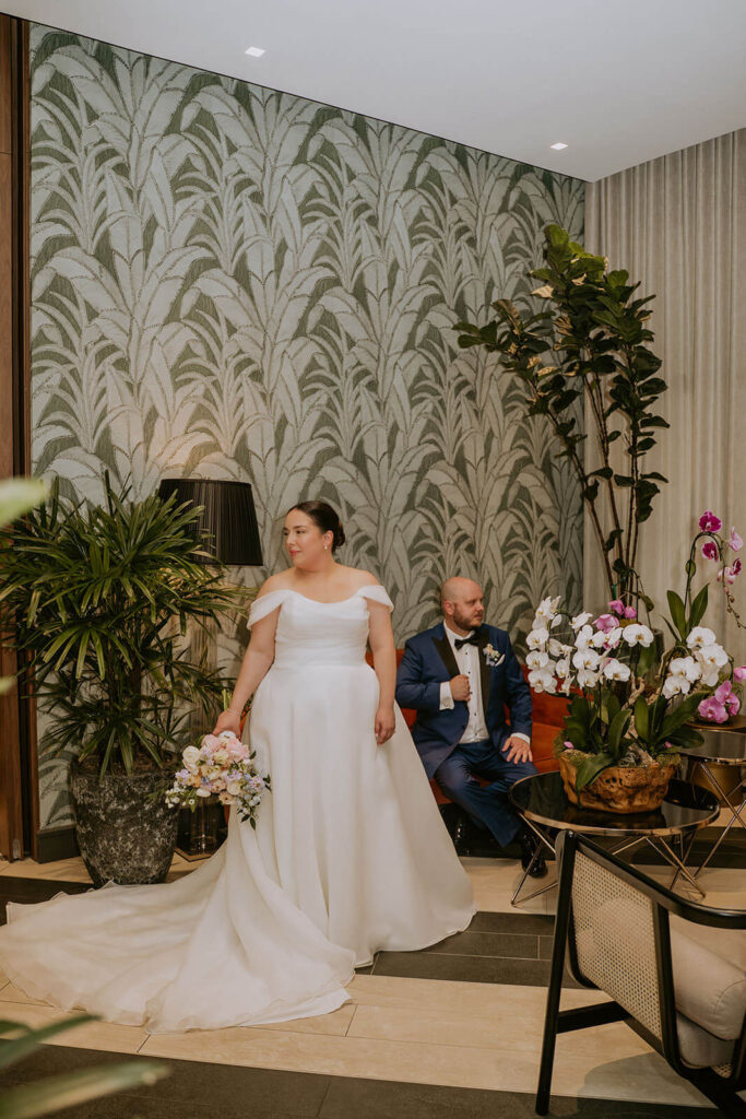 a couple poses on a couch in a miami hotel lobby on their wedding day