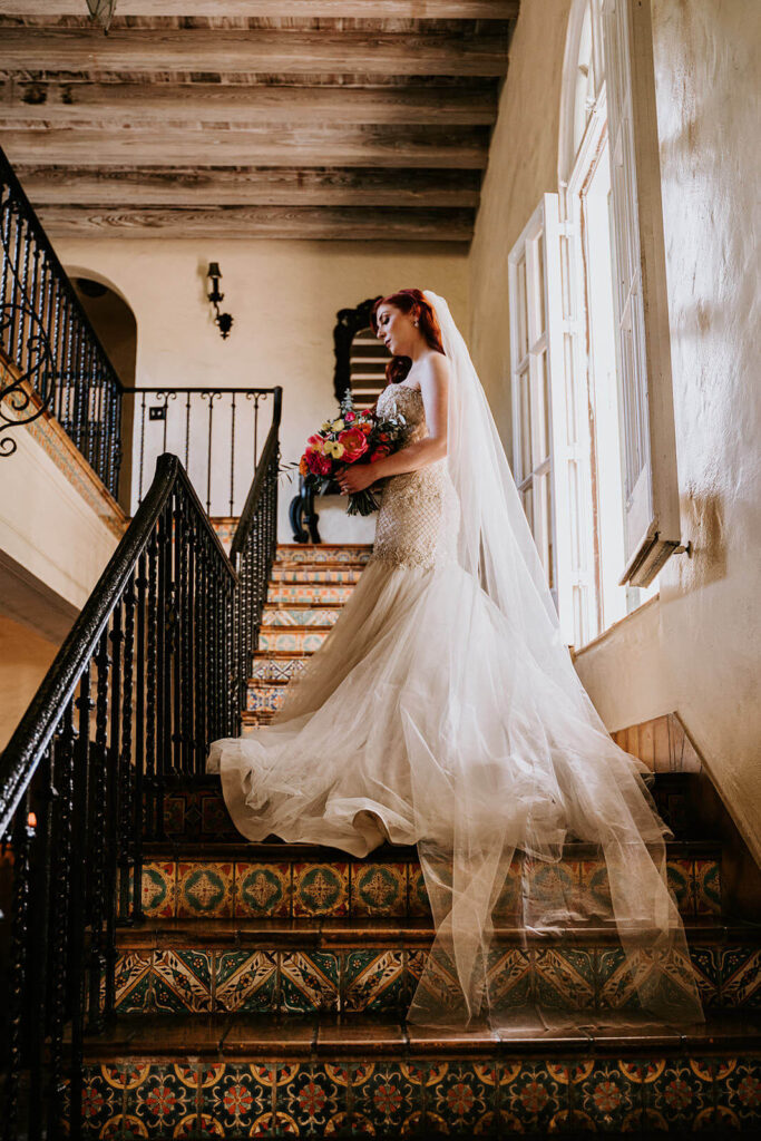 a bride poses with her bouquet on the staircase