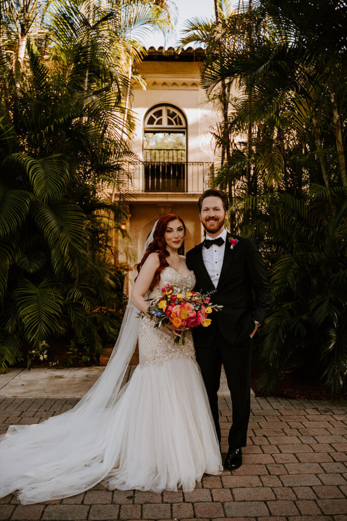 a bride and groom pose in front of their wedding venue - Villa Woodbine in Miami