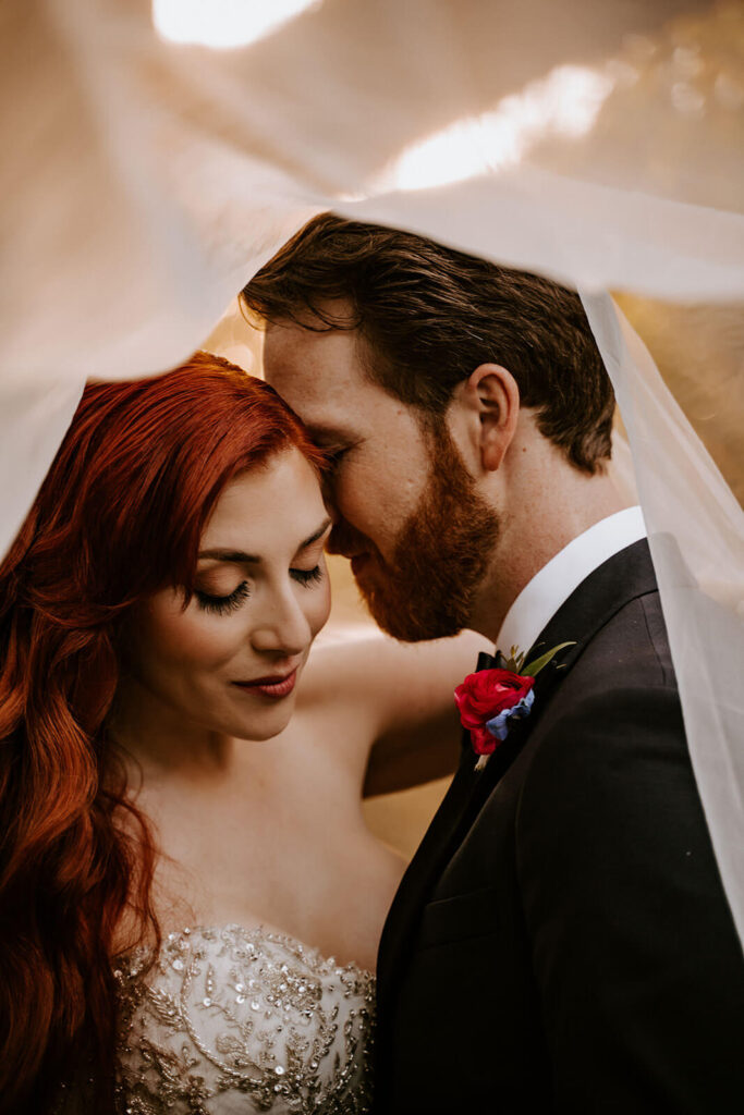 a bride and groom cuddle under the veil at golden hour on their miami wedding day 