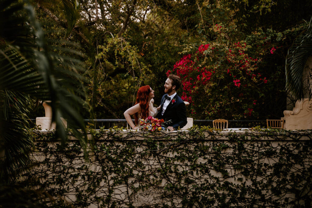 a bride and groom look at each other on the balcony