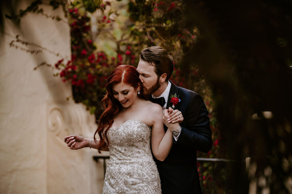 a groom kisses the back of his brides head on their wedding day
