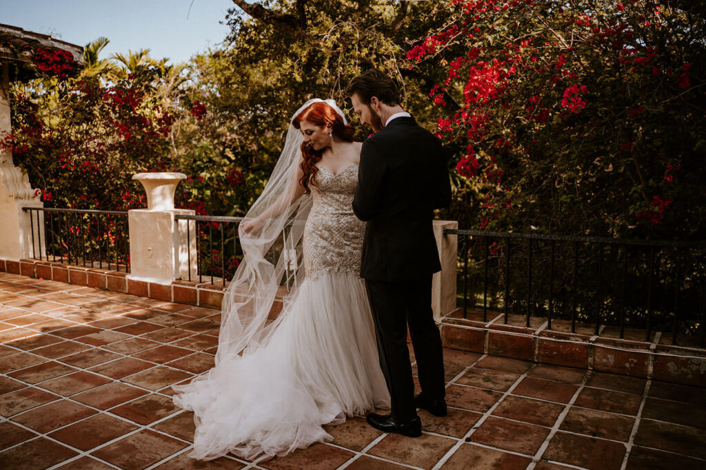 a bride shows her groom her veil during the first look
