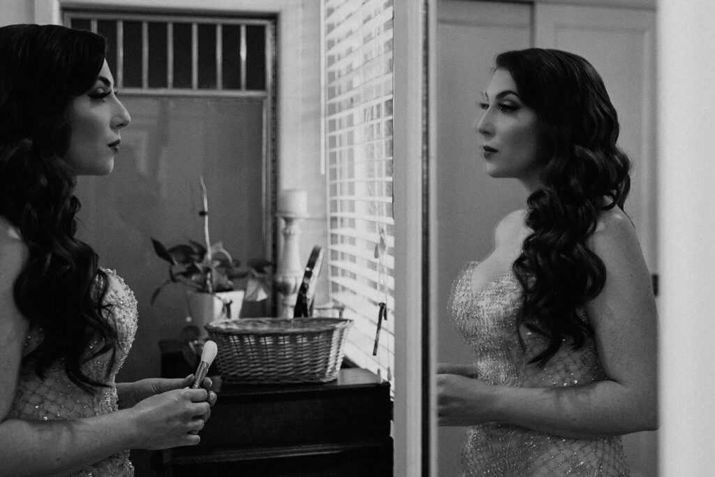a bride does her makeup in the mirror on her wedding day in Miami