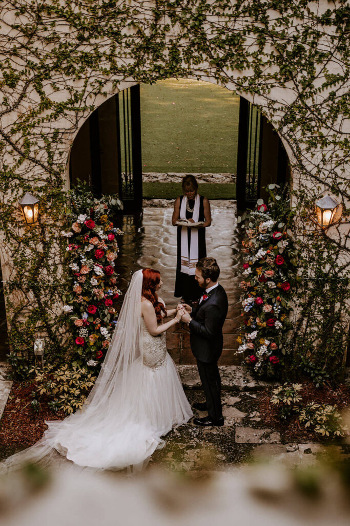 a couple holding hands at their ceremony with the officiant behind them