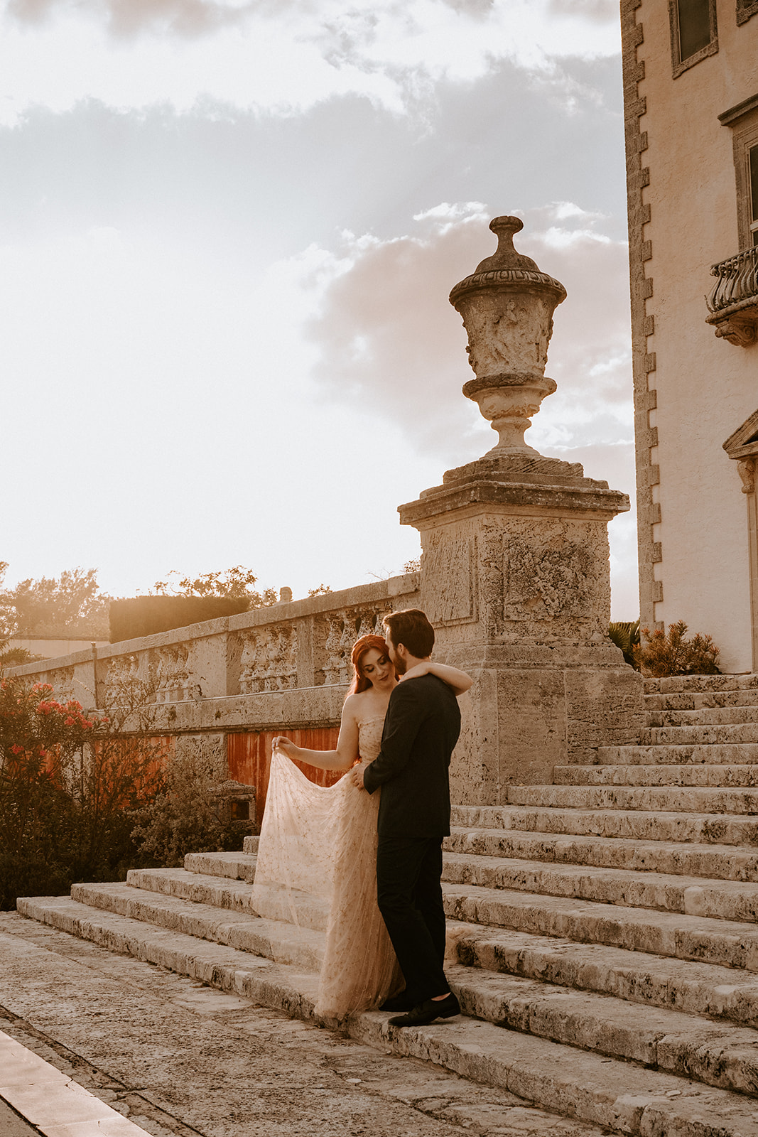 Man and woman pose for Vizcaya engagement photos at sunset