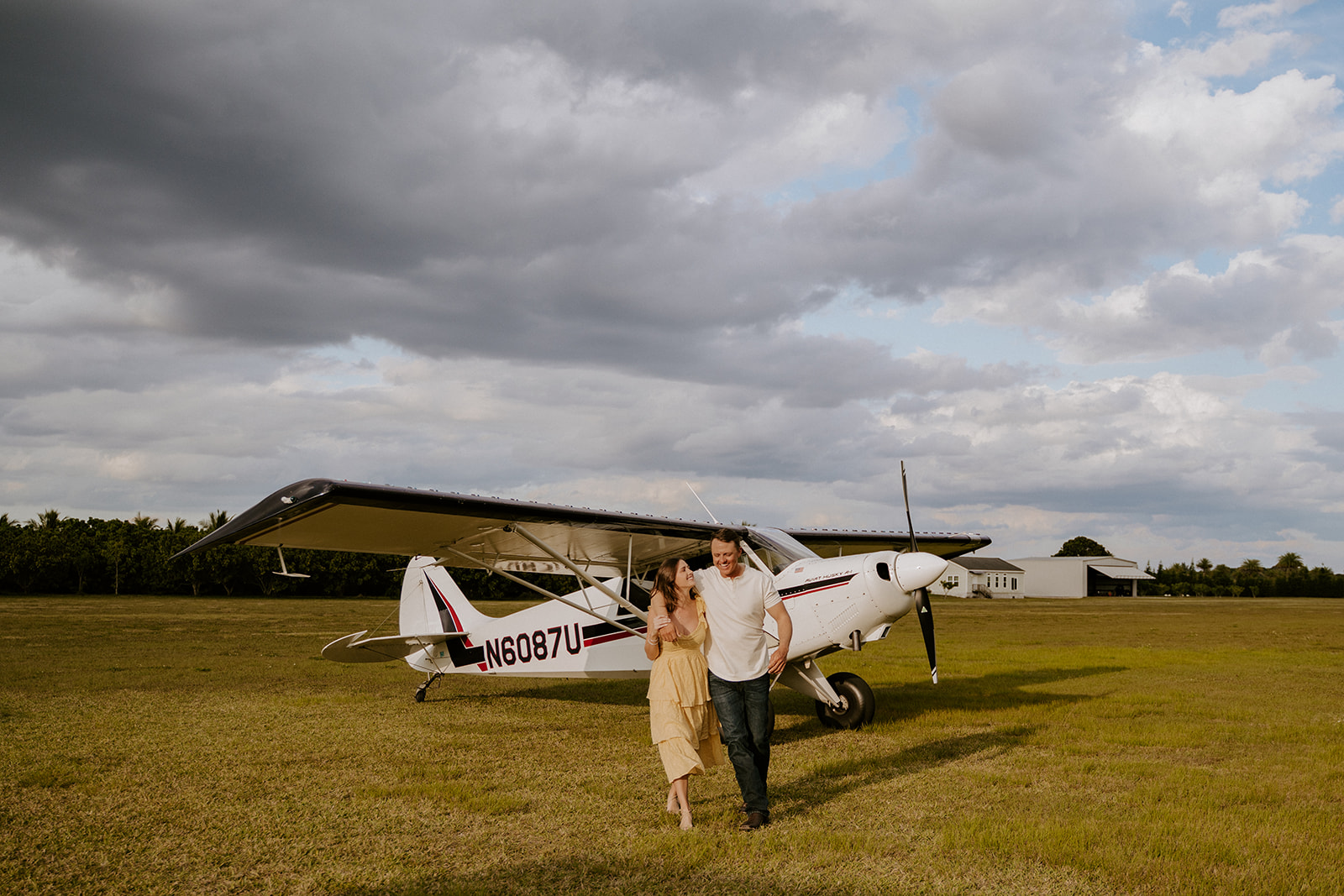 Man and woman walk in front of their airplane during their engagement shoot