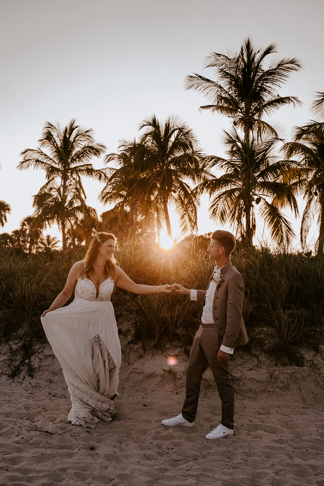 Bride and groom hold hands during sunset portraits