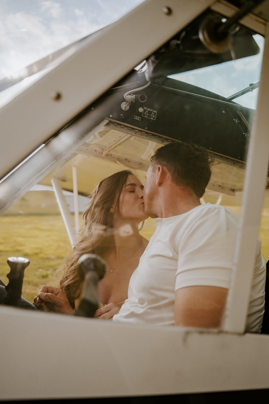 Couple kisses in airplane at their unique engagement session