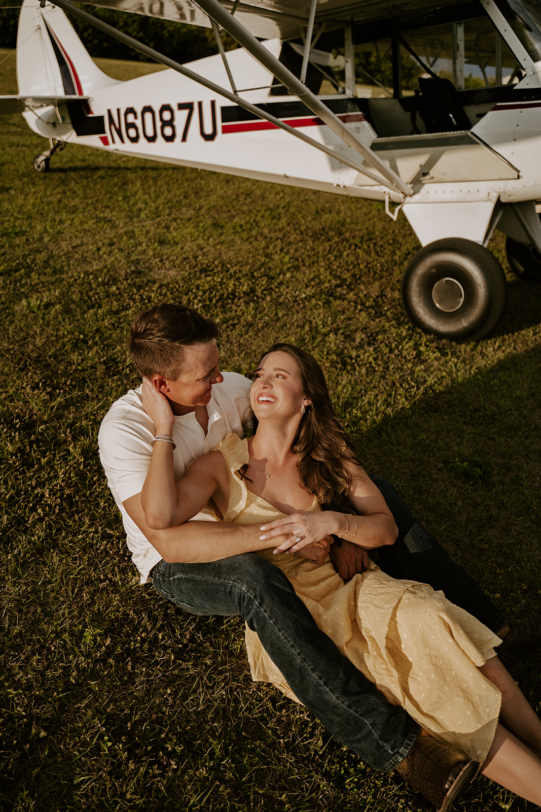 Couple sitting in front of airplane during their engagement photos