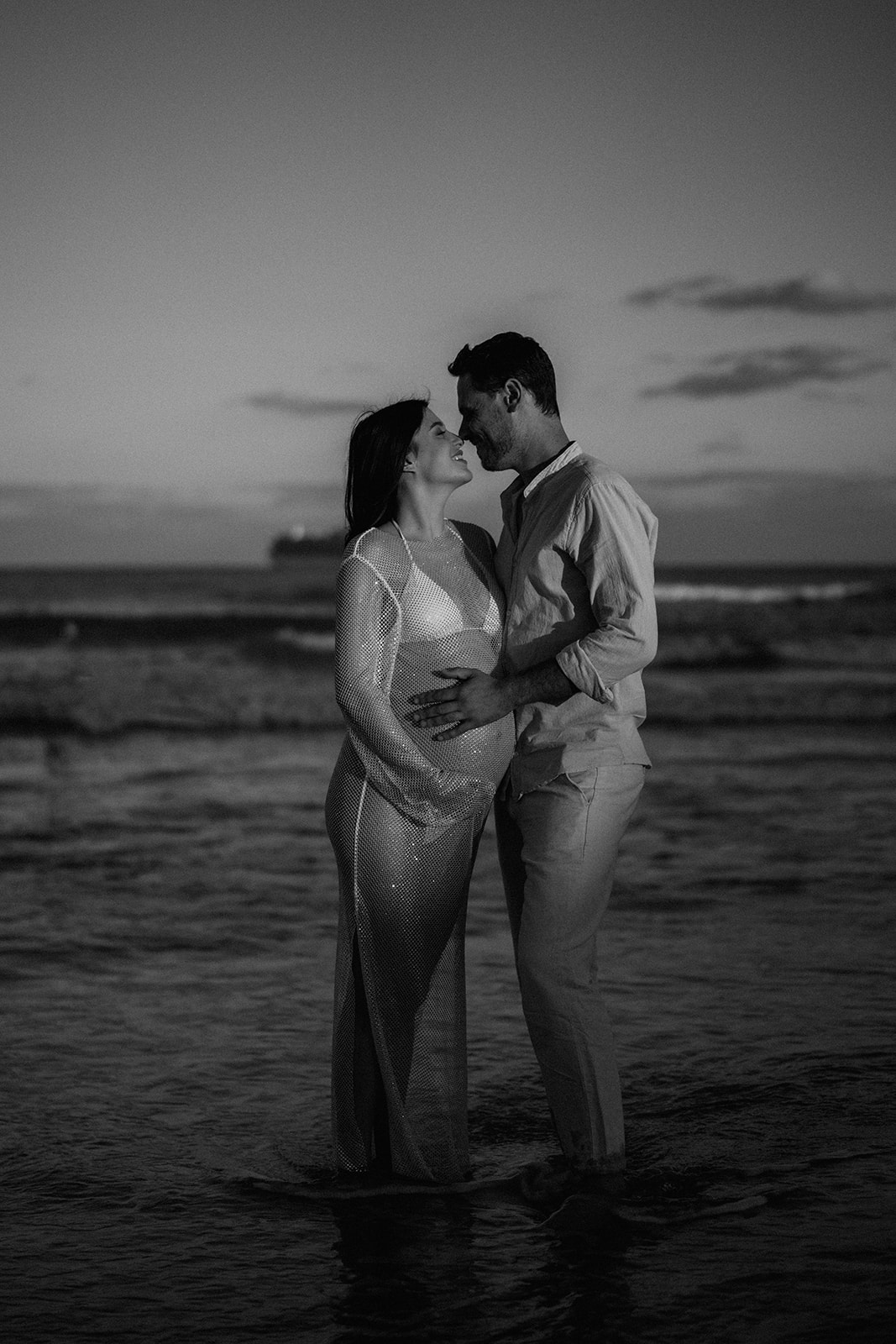 Black and white photo of couple at their beach maternity photoshoot
