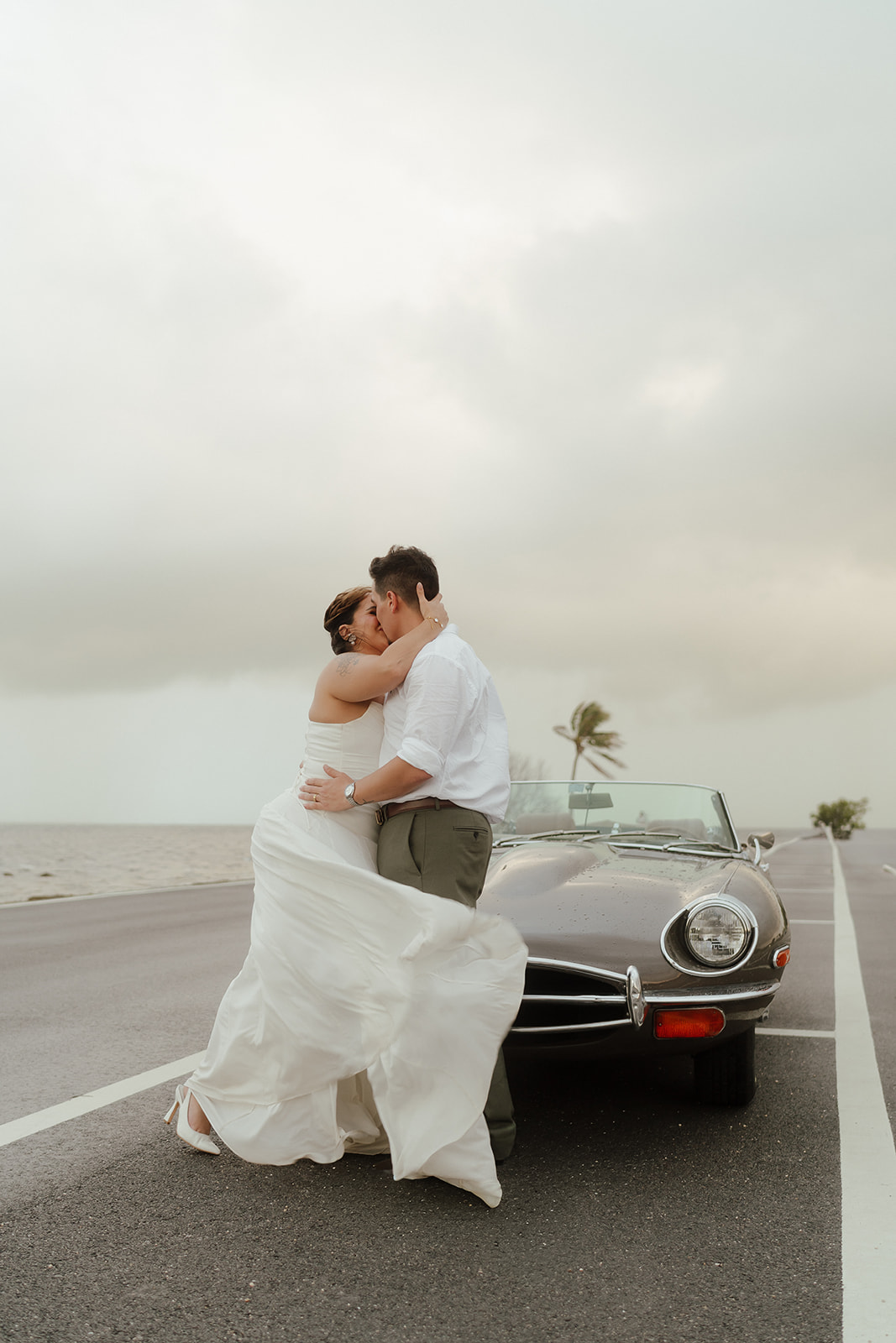 Couple kisses in front of a vintage car during their engagement session