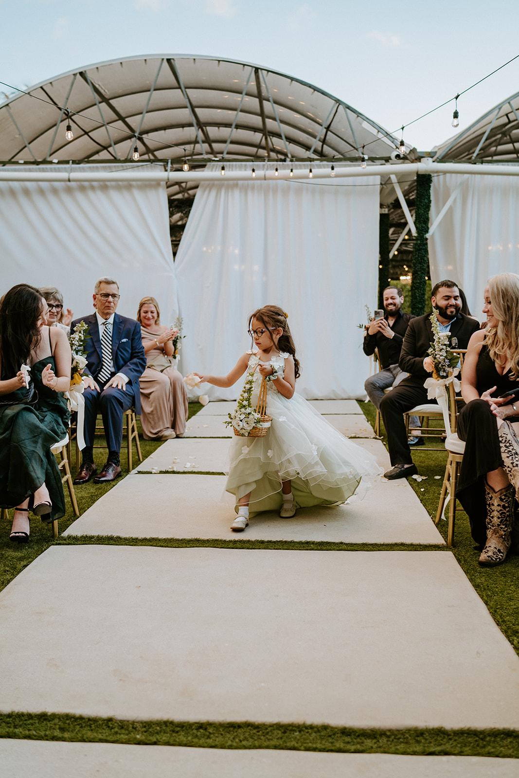 Flower girl walks down the aisle at the Vignette Gardens wedding