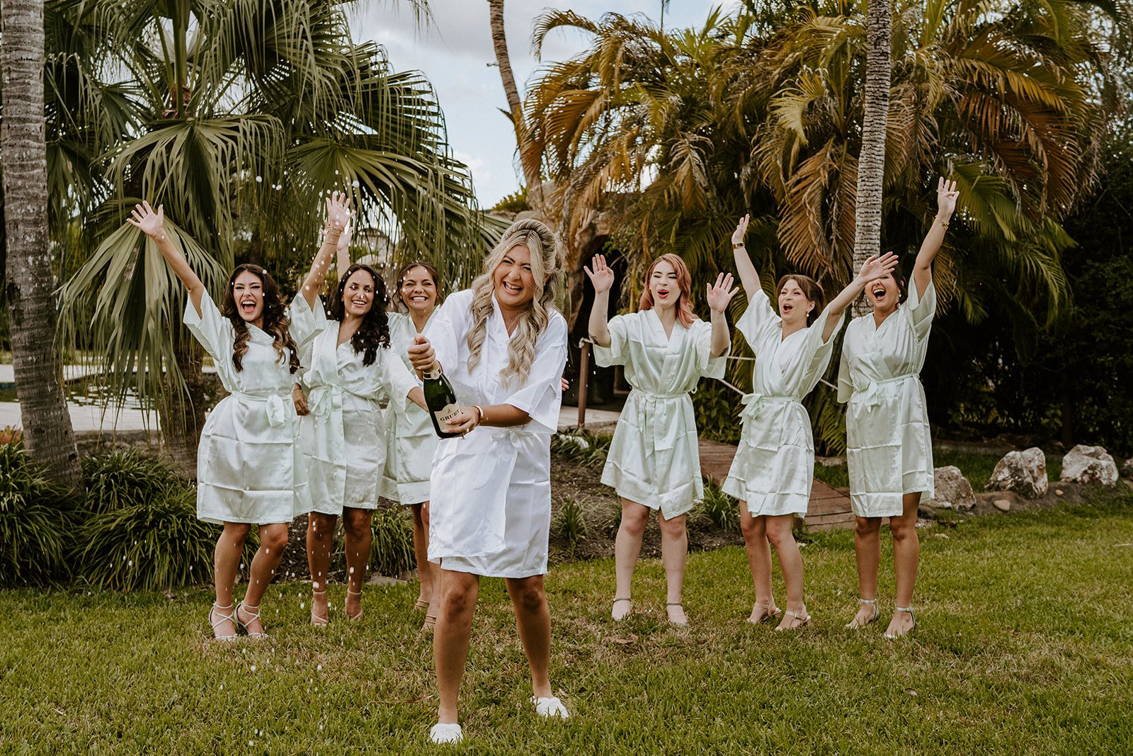 Bride popps champagne at Vignette Gardens wedding